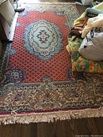 Full view of the silk oriental rug showing the red lattice field, central medallion, floral borders and fringed edges.