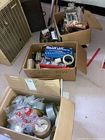 Photo showing three boxes filled with assorted hand tools, socket sets, tapes, and other utility items.