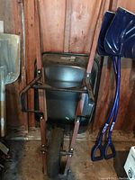 Side view of the wheelbarrow showing wooden handles, black metal tub, and front pneumatic wheel.