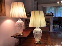 Two matching cut glass leaf pattern lamps on table with pleated shades lit.