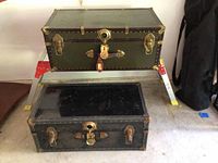 Photo of stacked green and black vintage trunks showing exterior condition and hardware.