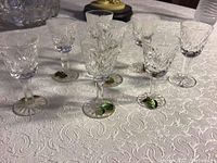 Eight cordial glasses grouped on table with labels visible
