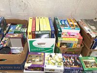 Four boxes containing assorted puzzles; visible puzzle boxes of various piece counts and brands