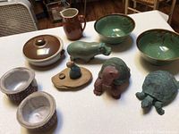 Overview of all ceramic bowls, pitcher, and animal figurines on table