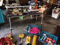 Wide view of folding table and floor displaying full assortment of cords, tools, lights, baskets