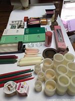 Overview of all candles and candle accessories laid on a white surface including flameless candles, taper candles, pillar candle, tealight holders, and boxed items.
