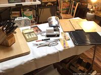 Wide view of cutting utensil set on table including knife block, cutting boards, sharpeners, and forks.