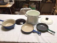 Overview of all four cookware pieces on a white tablecloth
