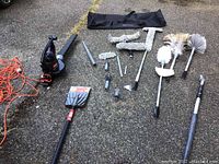 Full lot layout showing leaf blower, extension poles, multiple duster heads, scraper, and carrying bag on pavement.