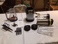 Complete set of Ninja Pro System 1100 components including blender base, attachments, go cups, and manual laid out on a table.