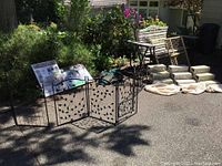 Full view of 4 free-standing metal pet gate sections with leaf pattern and 3 sets of pet stairs with step covers, beige fleece blanket in front, pet bag at back