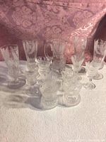 Full view of pitcher and all glasses on white cloth with pink damask backdrop