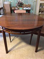 Dining table with leaf attached showing walnut grain top and tapered legs