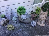 Full arrangement of statues, planters, bench, lantern and greenery against house siding