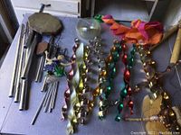 Overview of multiple wind chimes on a table including bamboo wind chimes, metal tubes, and metal spirals in various colors.