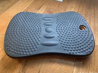 Top view showing black textured surface with bumps and an orange edge with a carry hole.