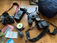 Overview of two camera bodies, lenses, strap, manuals, flash, bag, film accessories and blower