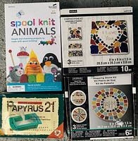Four kids craft kits including spool knit animals, stepping stone kits, and Papyrus 21 paper making kit displayed on a table.