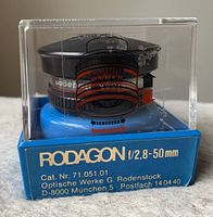 Focus on front and side of the lens within its original display box showing Rodagon branding and model details on the box.