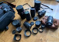 Overview of lenses, converter, multiple hoods and pouch laid on wooden floor