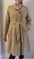 Front view of beige wool cashmere coat shown on a model, featuring button closure and tied belt around the waist.