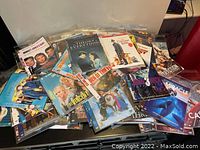 Photo of scattered DVDs showing various movie titles and covers including The Theory of Everything, The Other Woman, Dead of Thieves, and others.