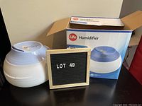 Photo of the round humidifier sitting next to its original box and a lot sign.