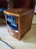 Front-left angle view of the rectangular wooden-finish electric heater showing control panel and vent