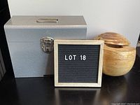 Photo showing both the gray metal file holder with handle and lockable clasp, and the natural wood oval container with swivel lid.