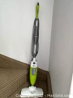 Full view of the green and white Smart Living Plus steam mop standing upright with cord wrapped around the handle.