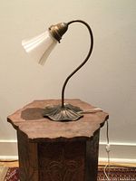 Photo of vintage table lamp on wooden surface with frosted glass shade and brass lily pad base, light off