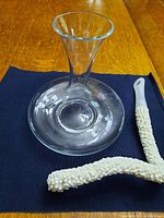 Top view of clear glass wine decanter with flexible white bristle cleaning brush next to it on dark cloth.