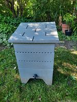 Overall front view of the worm composter with lid closed and spigot visible at the bottom front.