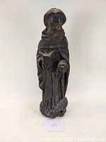 Front view of carved saint figure holding staff and book.
