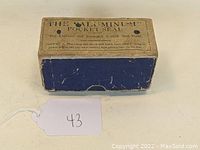 Original rectangular box of Aluminum Pocket Seal, beige top with blue bottom, text on top describing the product as the lightest and strongest pocket seal made.