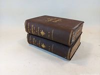 Side view showing stacked volumes with intact spine titles, volume numbers, and author names.