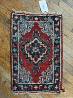 Top view of the hand knotted oriental mat showing the central medallion and colorful geometric border pattern in red, blue, black, and cream.