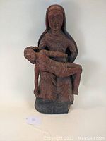 Front view of antique carved wood Pieta sculpture with good visible detail of facial features and draped clothing.