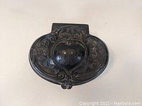 Top view of silverplate dresser box showing the embossed floral and heart-shaped motif on lid with dark patina and signs of oxidation