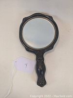 Full view of the round silverplate hand mirror with decorative Art Nouveau handle and frame.