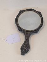 Full view of vintage Art Nouveau style hand mirror showing the ornate silver handle and mirror surface.