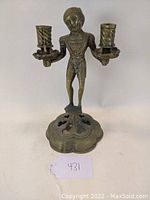 Front view showing the full figure holding two spiral candle sockets on a decorative circular base.