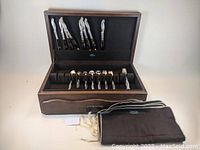 Open wooden chest with lift-top lid, removable tray, utensils and protective cloth liners.