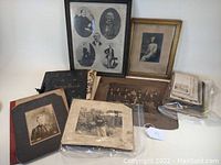 Wide view of collection displaying framed portraits, scrapbooks, and various vintage photographs on table.