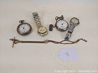 Full lot showing two pocket watches, two wristwatches, gold filled watch chain, and watch key.