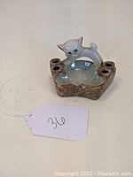 Front view of the porcelain ashtray showing the cat arching over the center and the three cigarette rests.
