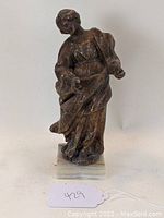 Front view of female religious figure statue with draped robes and textured finish.