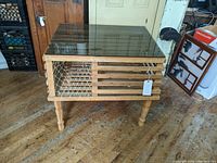 Front angle view showing the glass top, wooden trap-style frame with netting, and turned legs.