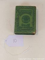 Photo showing front cover of green metal book bank with embossed title and crest marking.