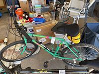 Full side view of the men's Rockhopper Specialized mountain bike showing green frame, black seat, yellow saddle bag, and black handlebars with gear shifters.